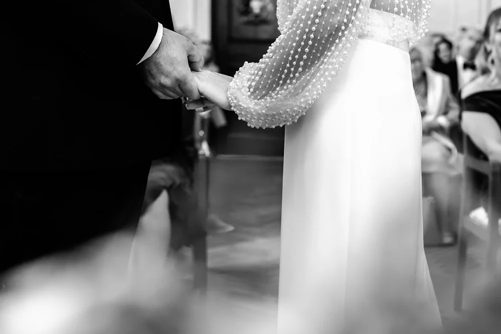 Close up of a pearl covered sleeve as the bride is helped into her dress