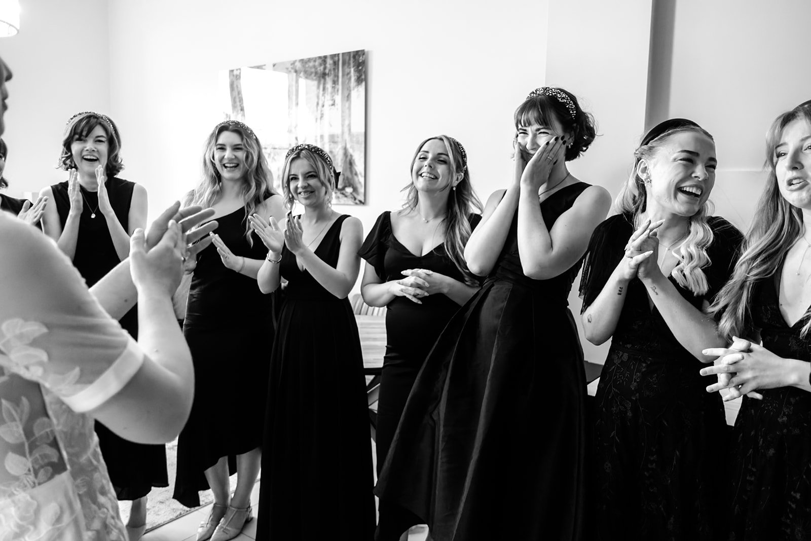 Bridesmaids applauding and welling up as the bride reveals her dress