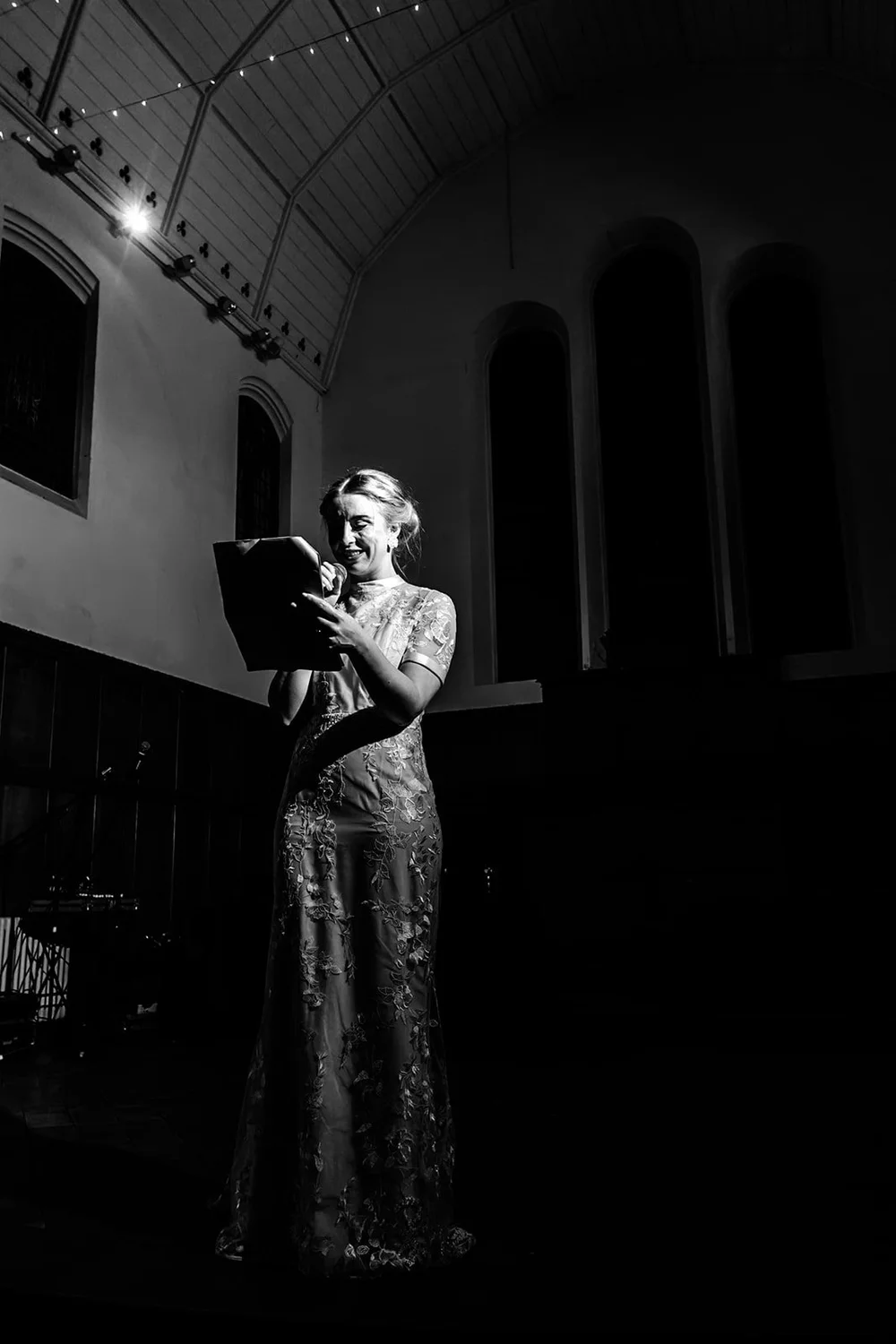 Bride standing in a shaft of light in a dark chapel