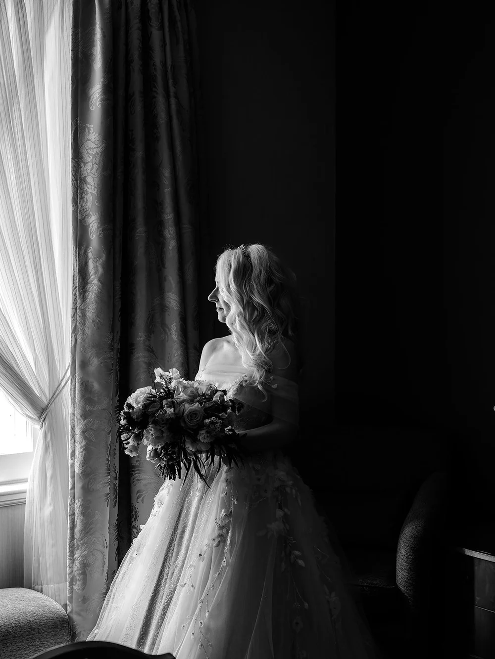 Bride holding her bouquet at a window in soft daylight