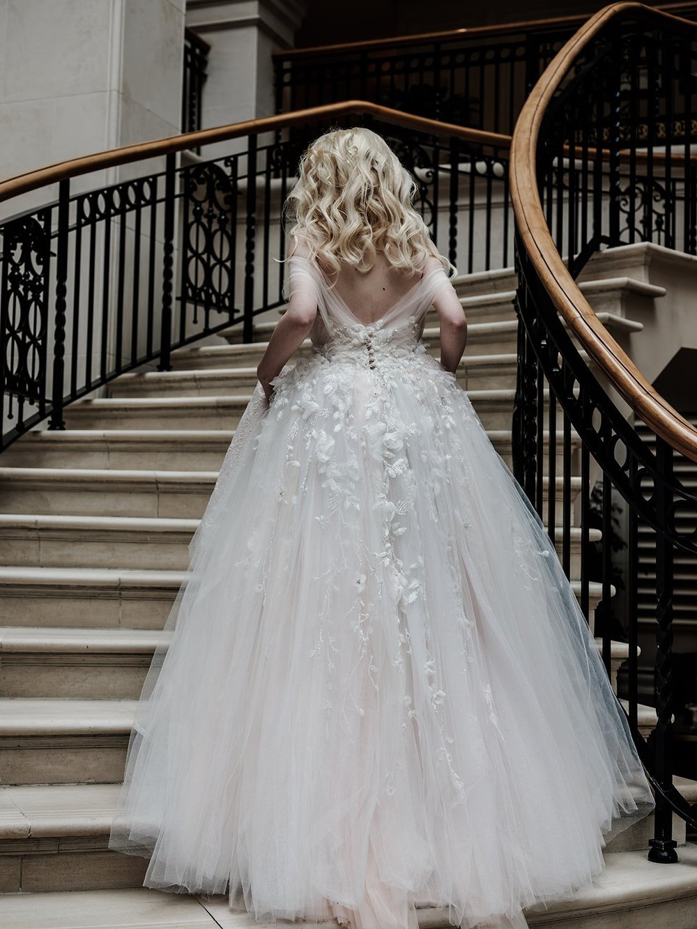 Bride walking up a sweeping staircase in her dress