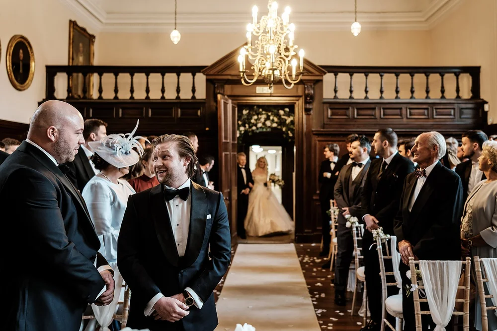 Guests turning in their seats as the bride enters the panelled ceremony room