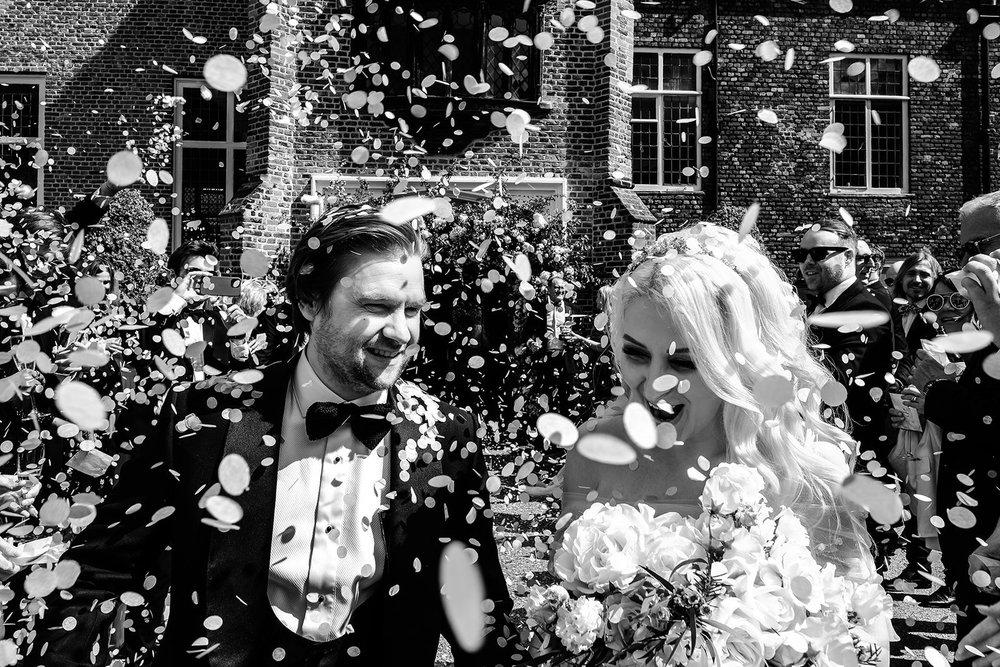 Bride and groom laughing through a confetti shower