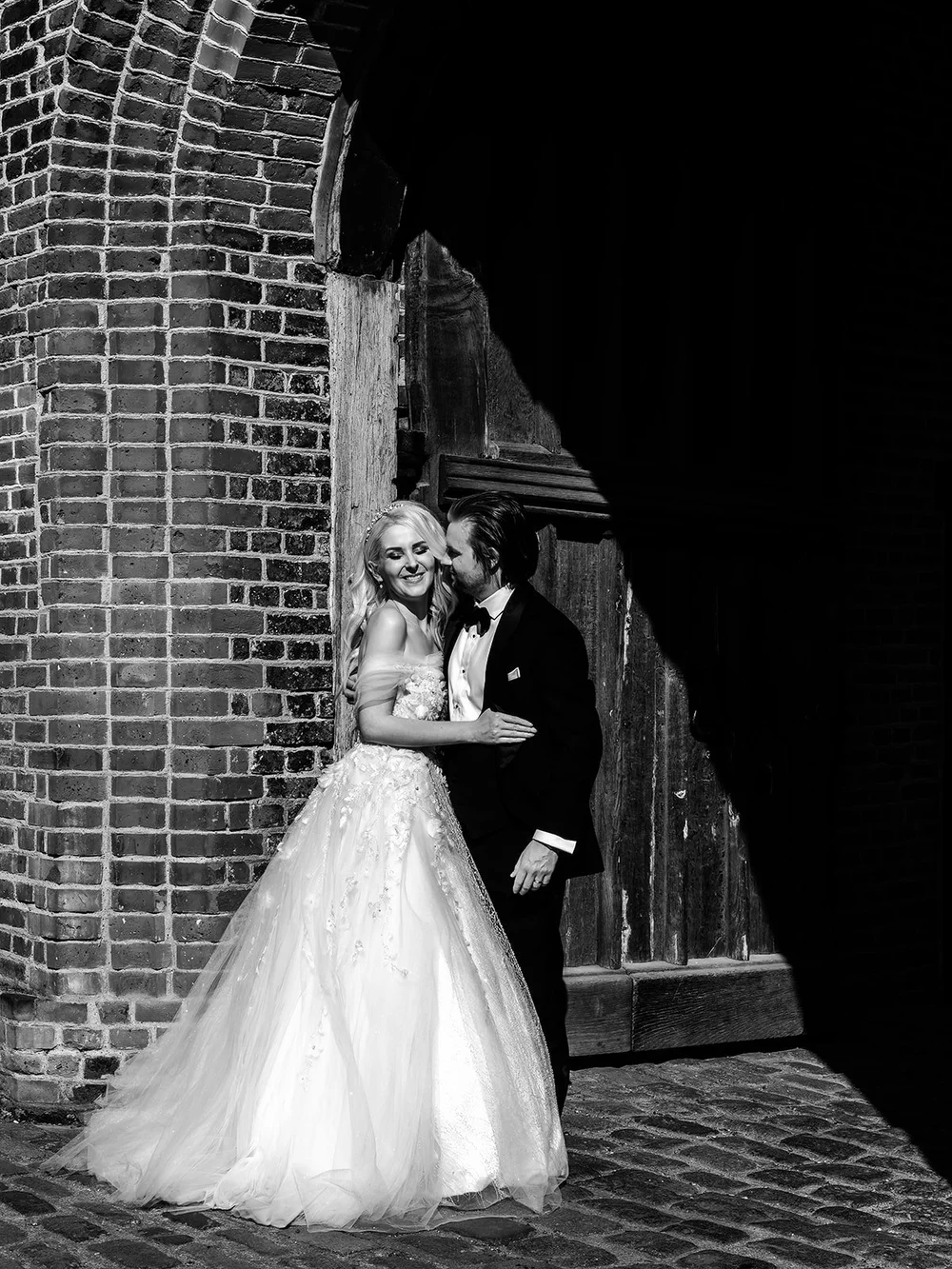 Bride and groom kissing in a brick archway