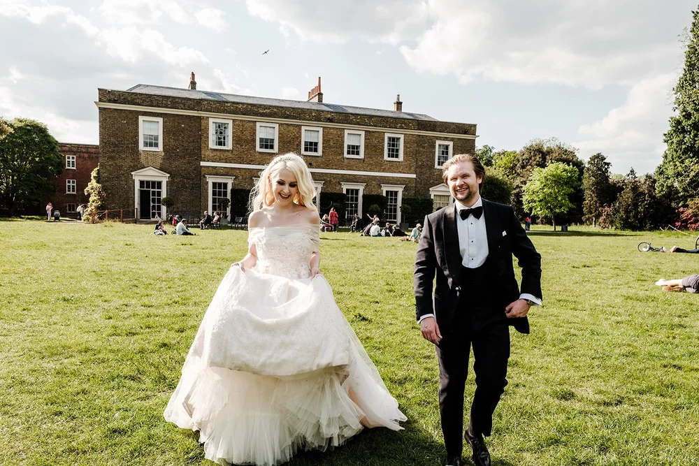 Bride and groom walking across the lawn in front of the house