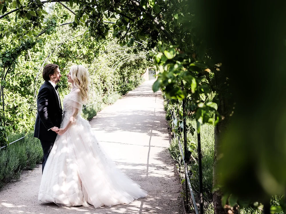 Bride and groom under a leafy garden arch