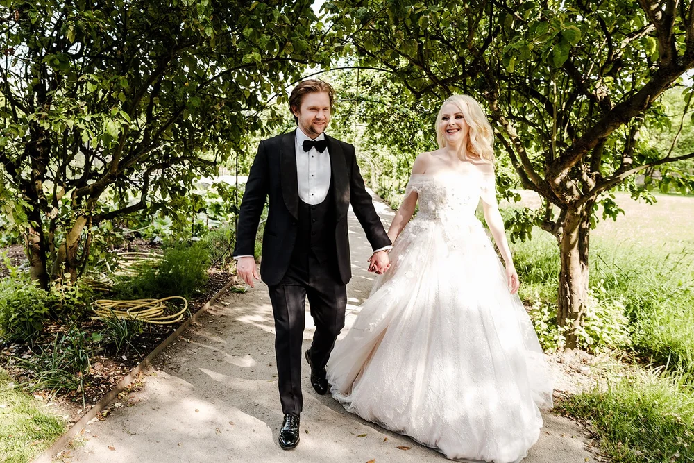 Bride and groom walking hand in hand through the garden