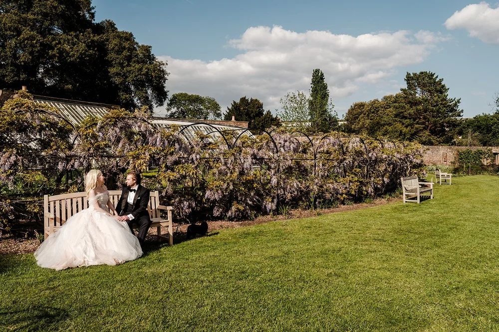 Bride and groom sitting together beside the wisteria walk