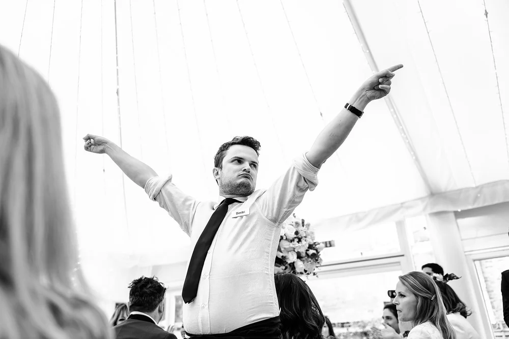 A singing waiter with his arms outstretched mid performance