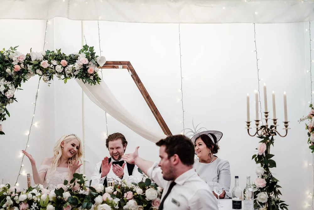 Bride and groom laughing at the top table during the speeches