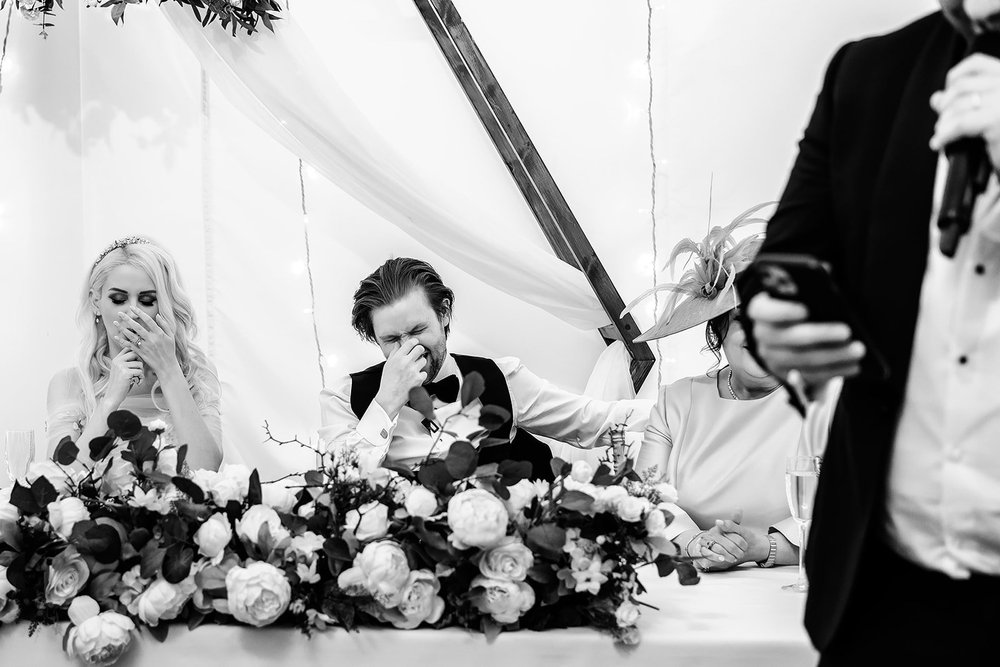 Bride and groom in fits of laughter at the top table