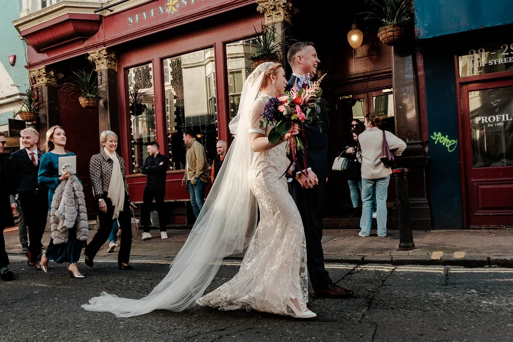 Grace&rsquo;s veil trailing as the wedding party walks through The Lanes in Brighton