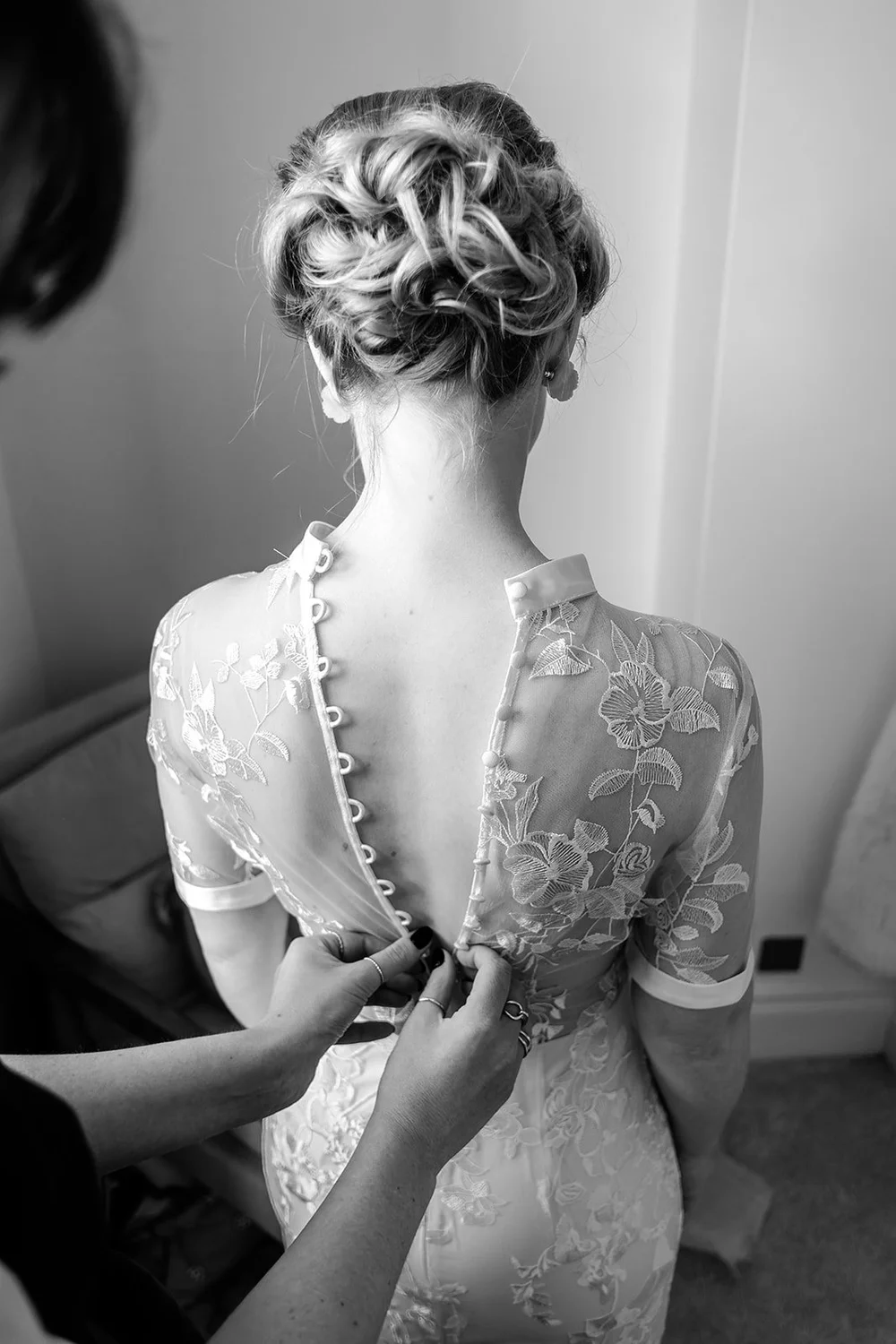 Grace&rsquo;s tea length lace wedding dress being fastened at the back