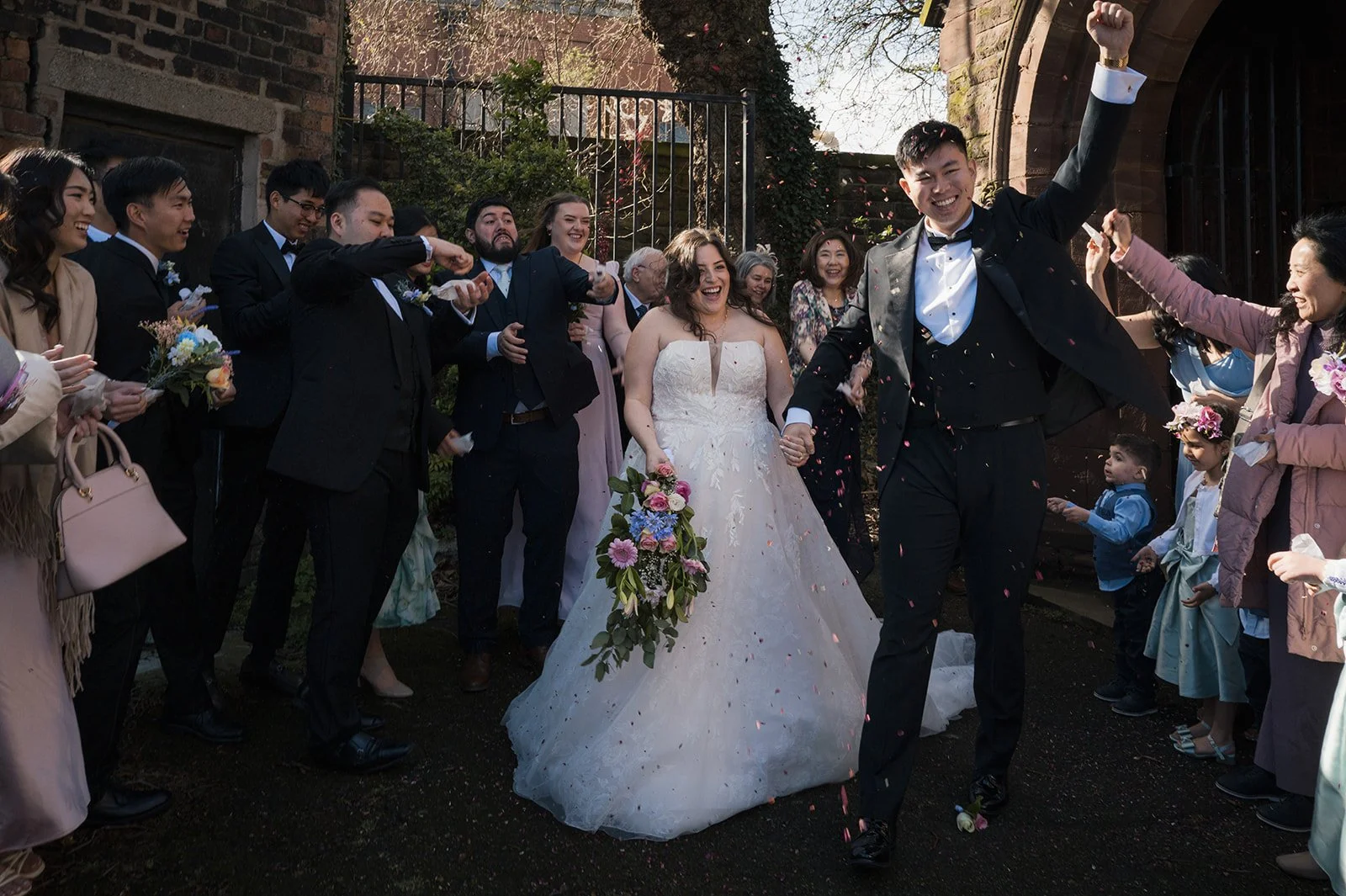 Luisa and Ray walking through confetti outside St Anne&rsquo;s Church, Old Swan, Liverpool