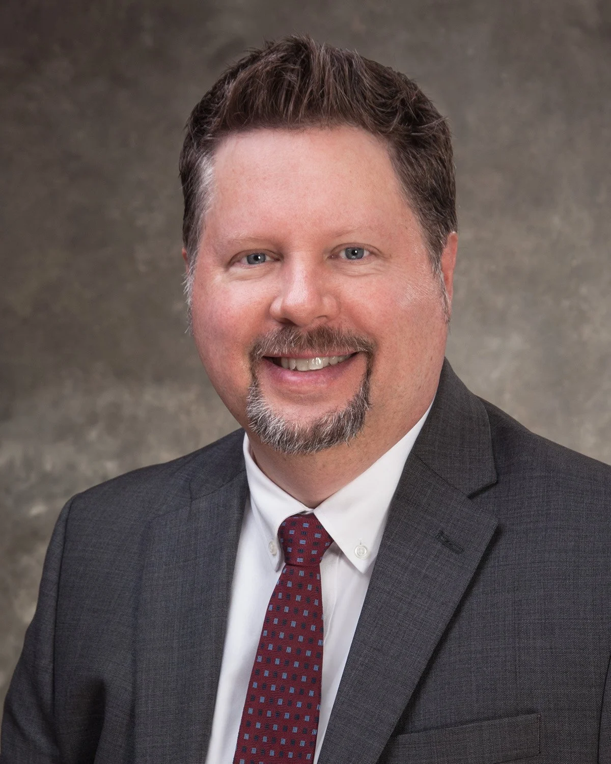 Headshot of Gregg Auby in a suit