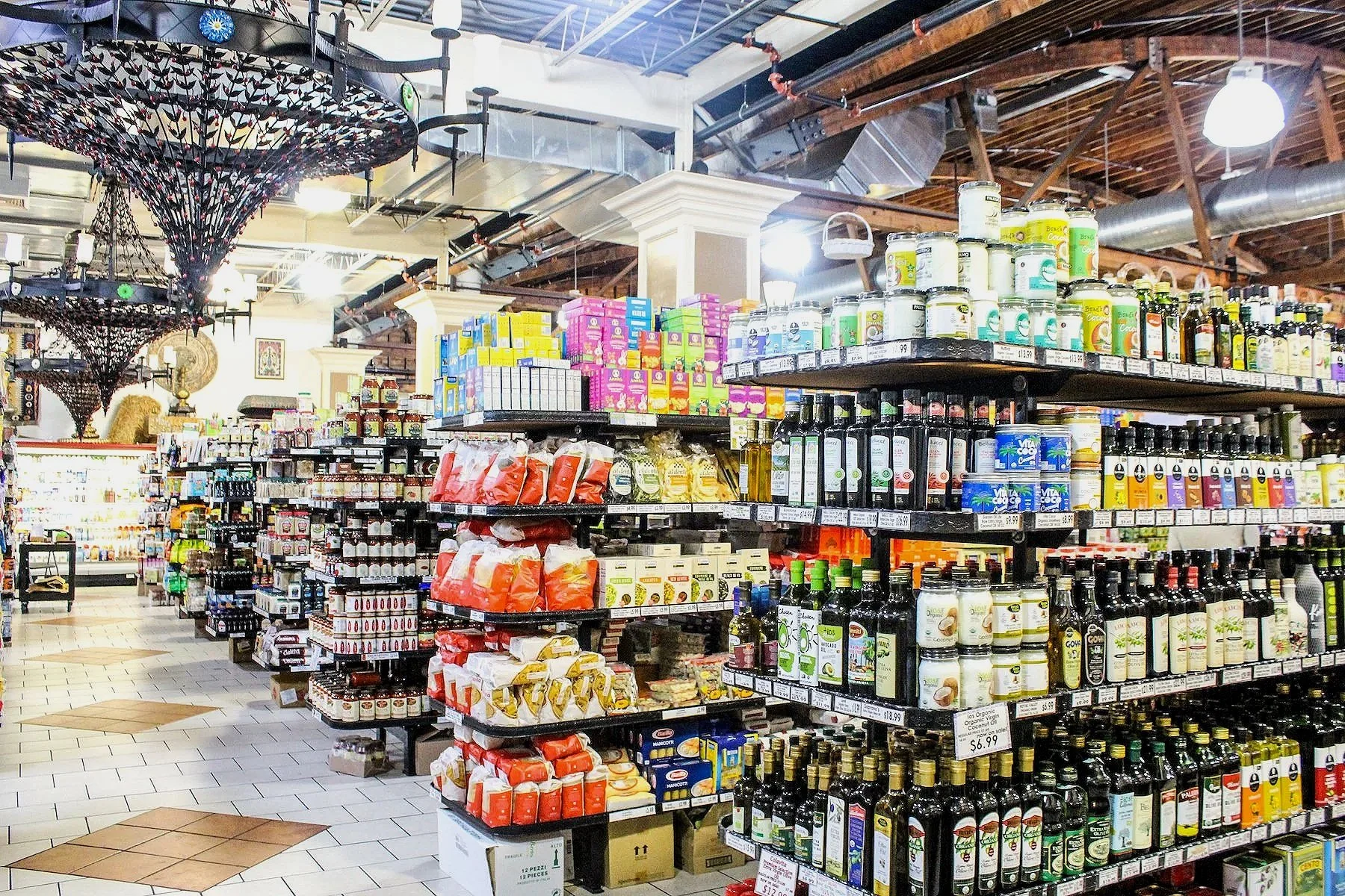 Interior of a grocery store with shelves stocked with bottles, jars, and packaged food items, including oils, seasonings, and snacks.