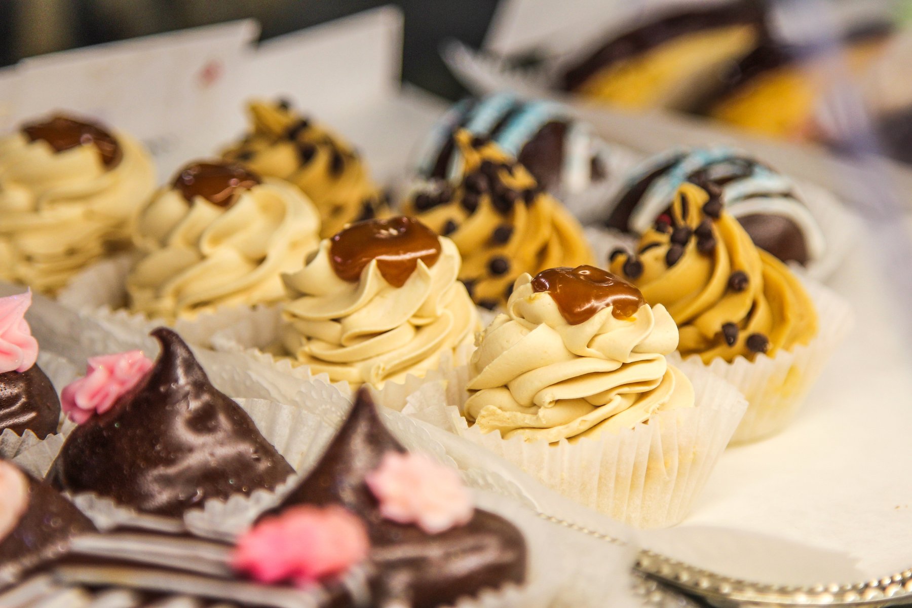 Assorted cupcakes with frosting and toppings on display.