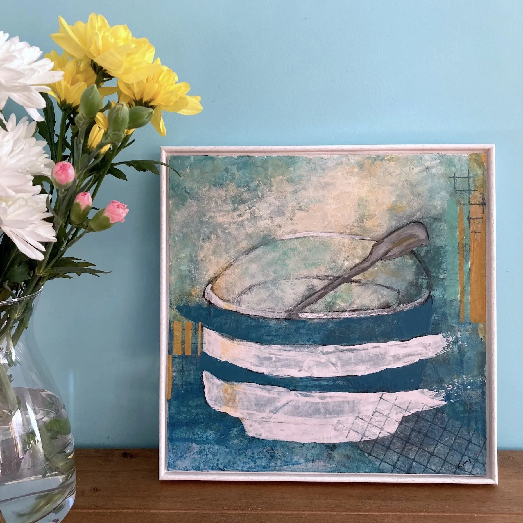 Insitu photograph of Lucy Mathers' painting called The Sugar Bowl, shown in a slime white wooden frame on a sideboard next to flowers in a vase