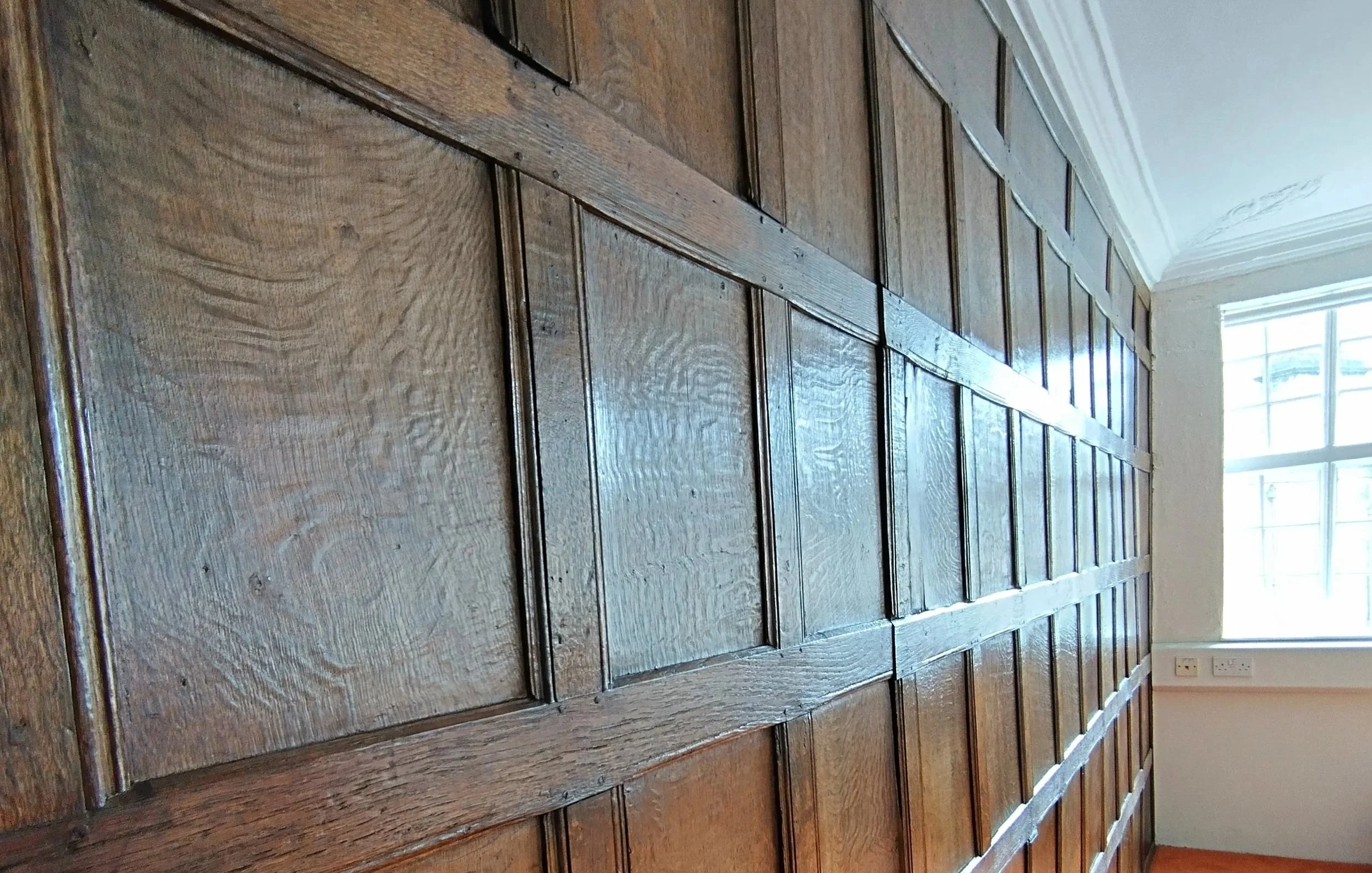 Restored oak‑panelled wall showing its texture and colour.