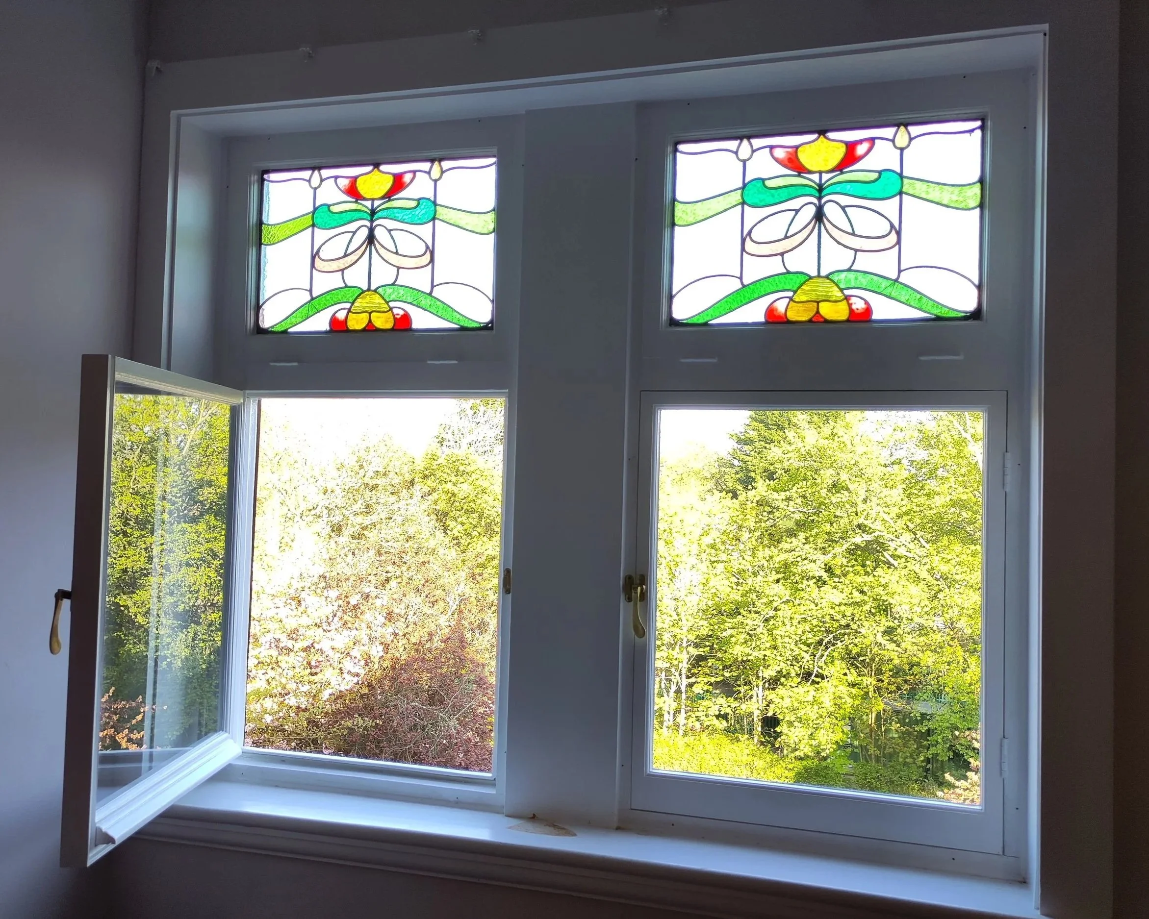 Double‑hung window with stained‑glass top panels, new openers made to match the original weatherproofing detail and rail profiles for private clients