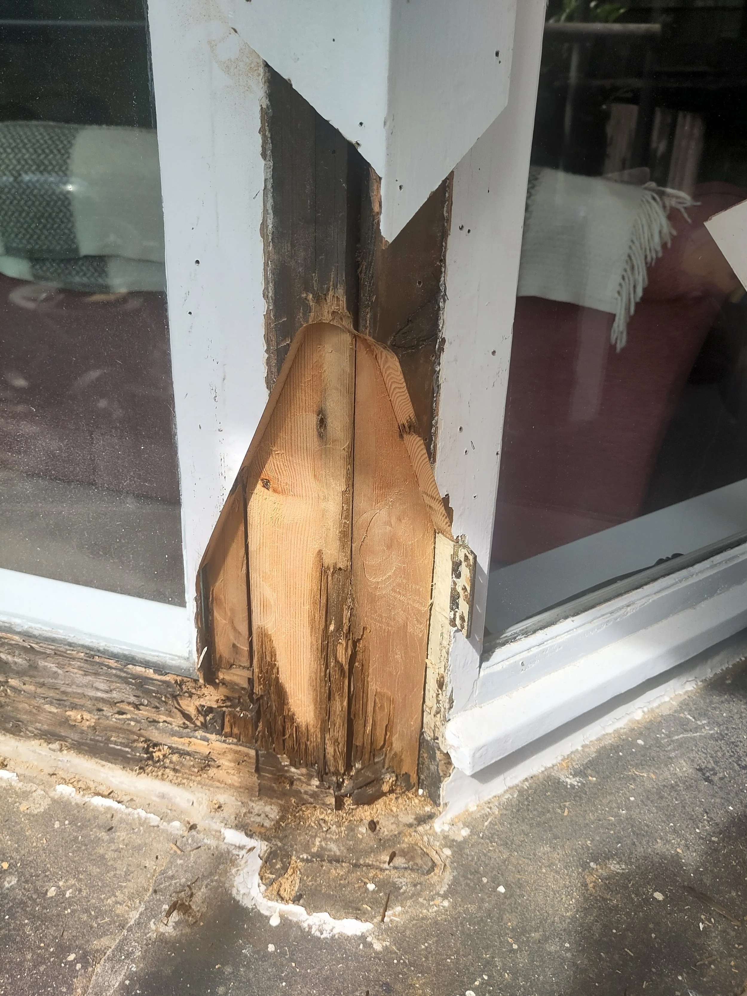 Corner of a bay window during restoration, showing removal of rotted timber and splicing‑in of new sections for a private client.