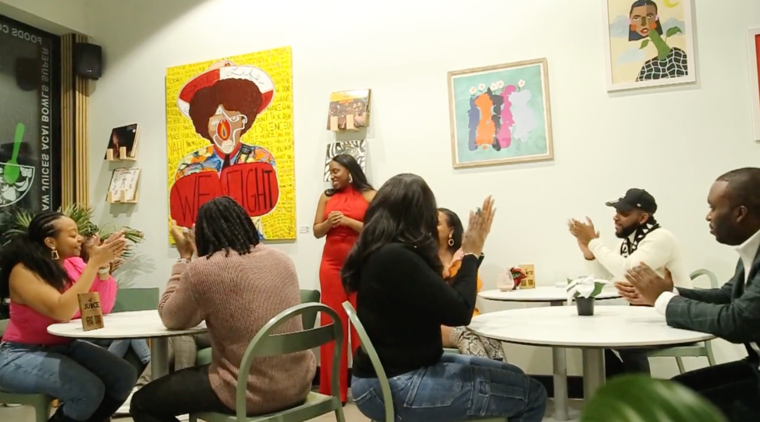 a workshop host and facilitator is standing in the center of a room while an audience is clapping and looking at the host.