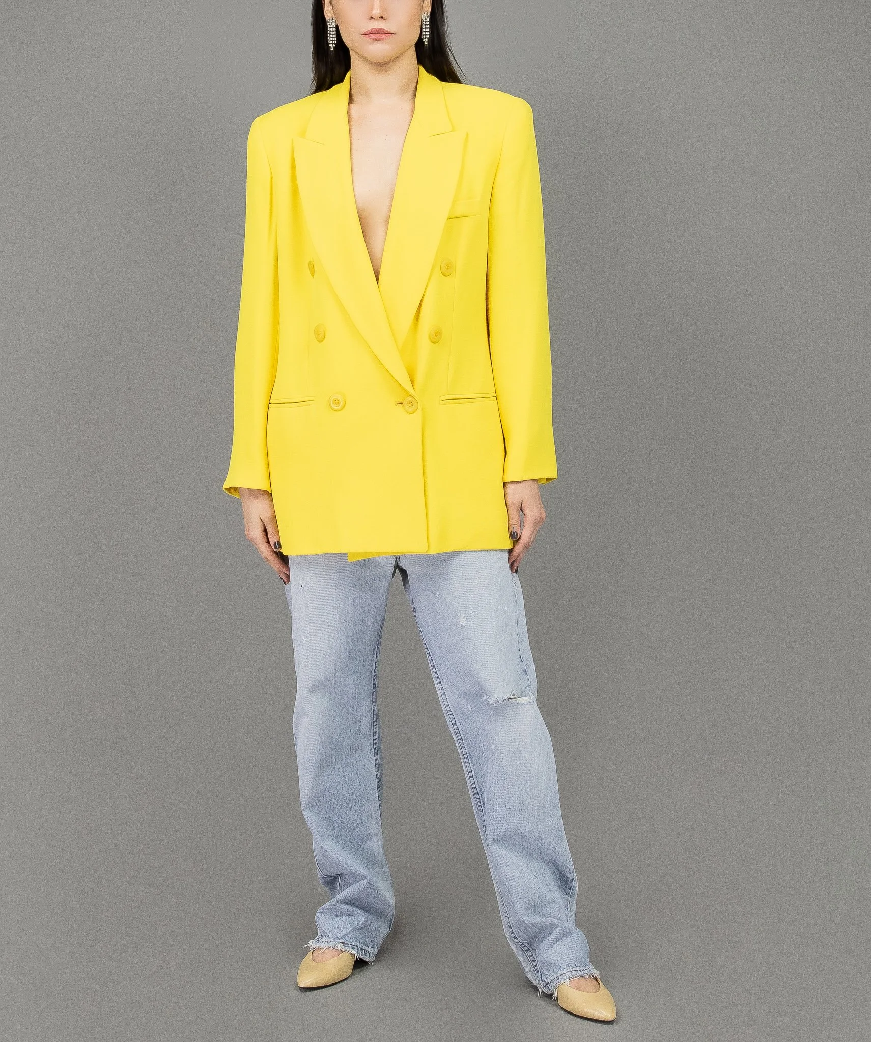 collector of vision model is wearing a size medium oversized yellow blazer with notched collar, double breasted, welt pockets, front buttons, style with baggy levis jeans, nude pumps, earrings