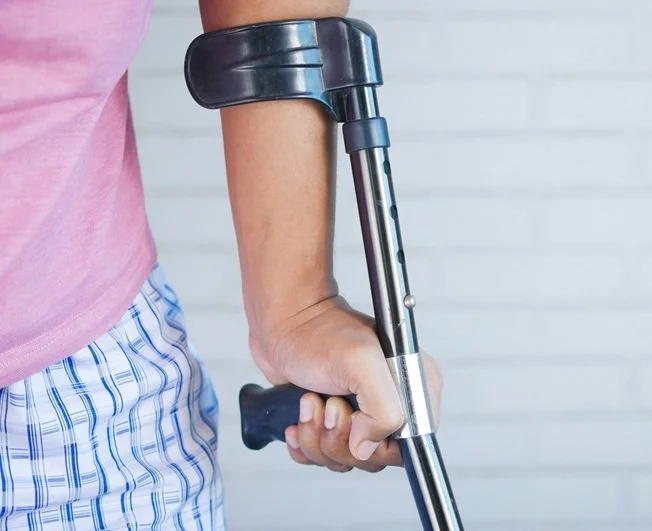 Close up of a person using a forearm crutch, with hand gripping the handle and lower arm supported by the cuff.