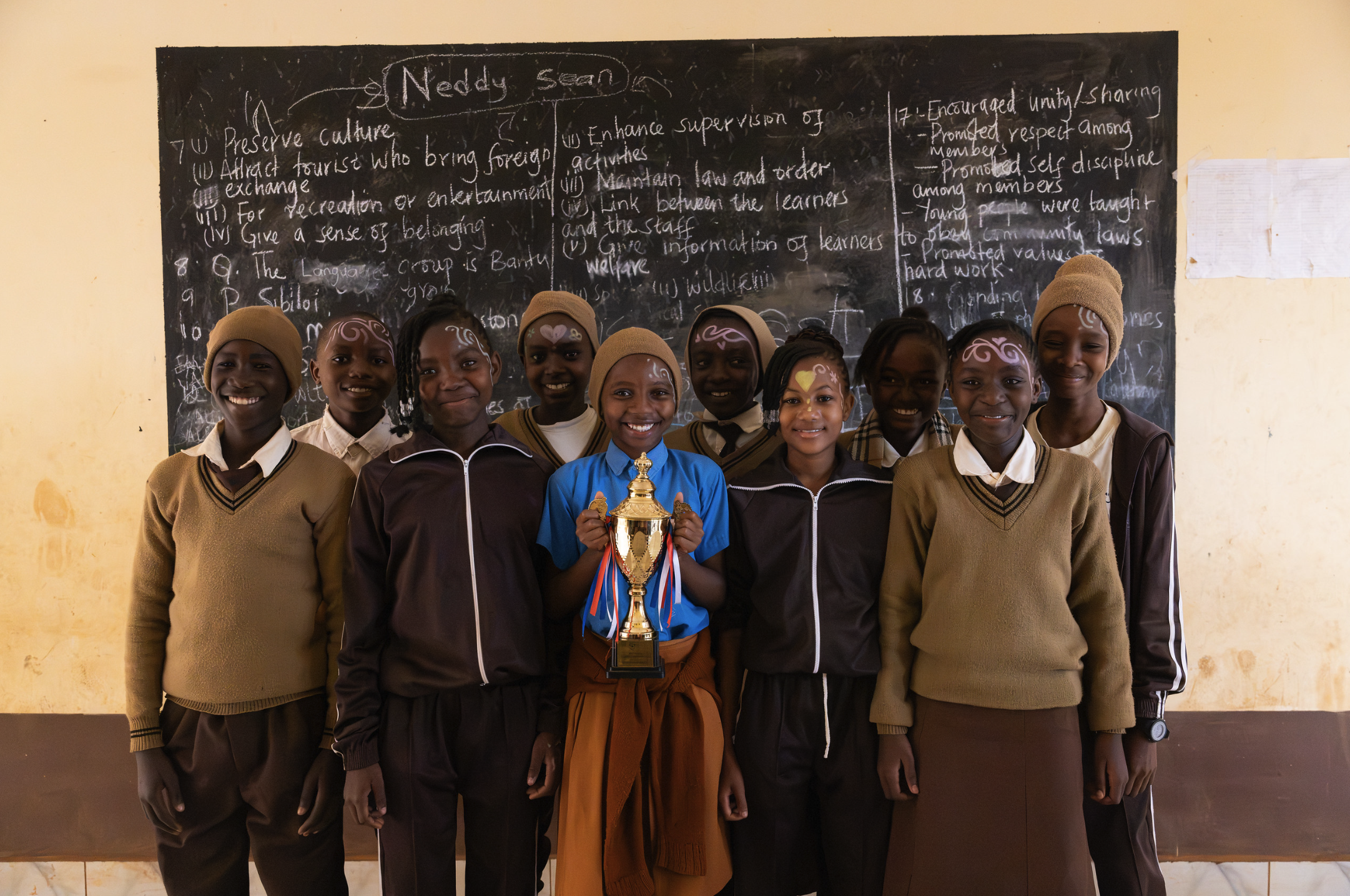 image of a group of students in a classroom in kenya proudly presenting an award they won