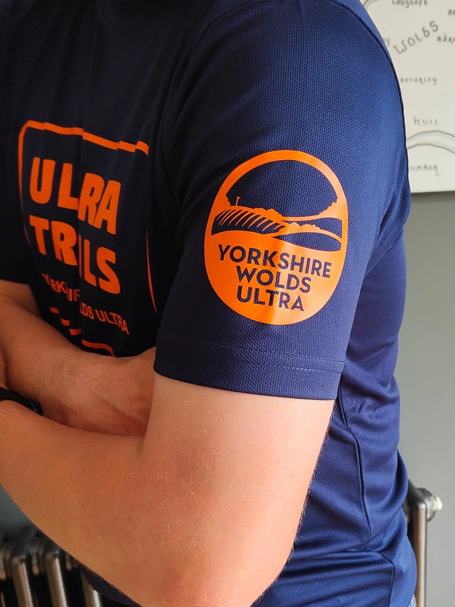 Person wearing a navy Yorkshire Wolds Ultra T-shirt with orange logo