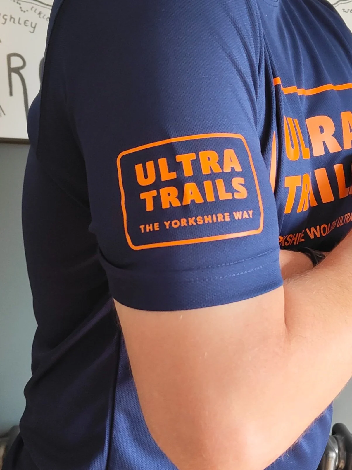 Person wearing a blue athletic shirt with 'Ultra Trails The Yorkshire Way' printed on the sleeve in orange letters.