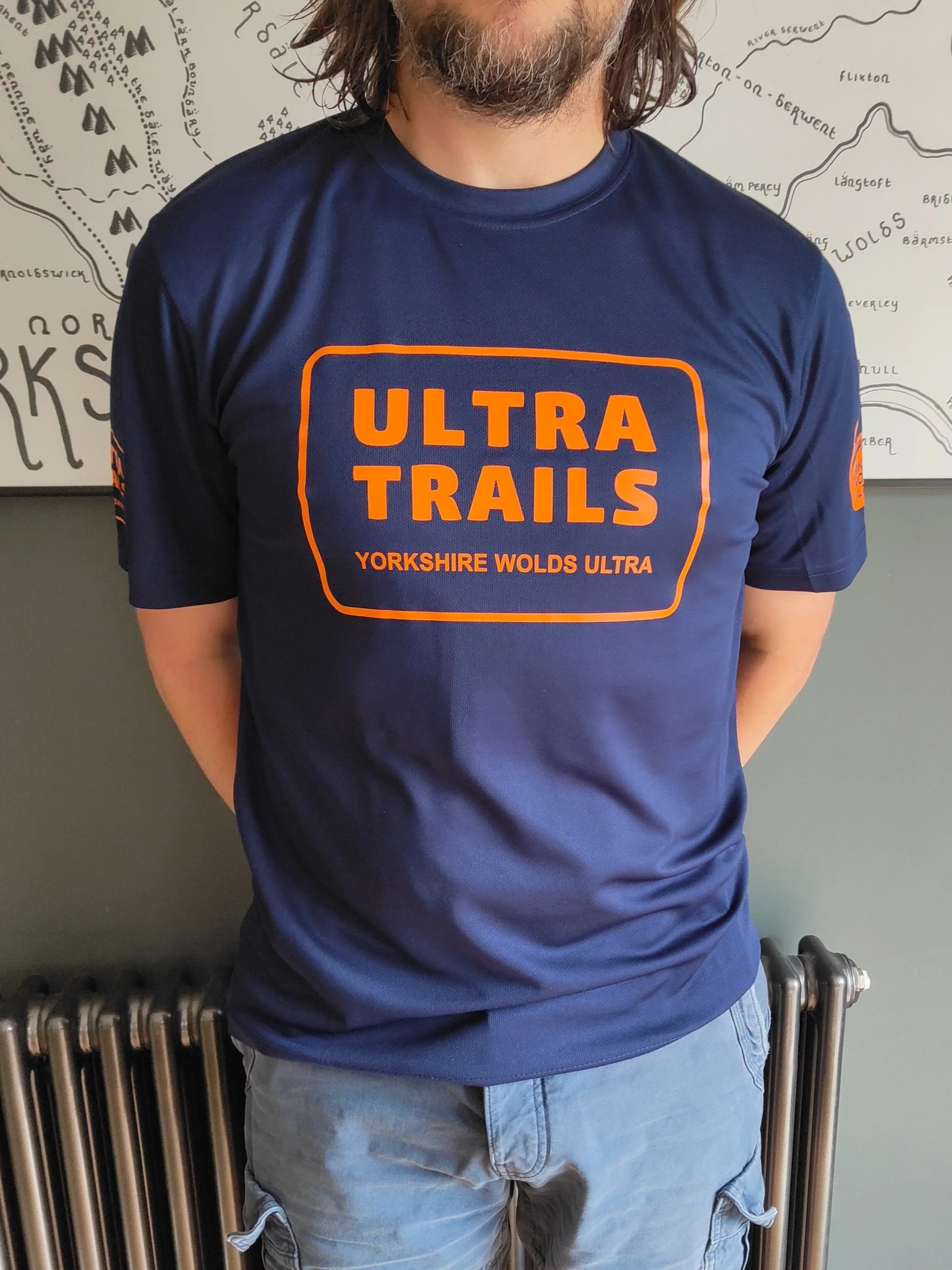Person wearing a blue "Ultra Trails" Yorkshire Wolds Ultra t-shirt in front of a map.