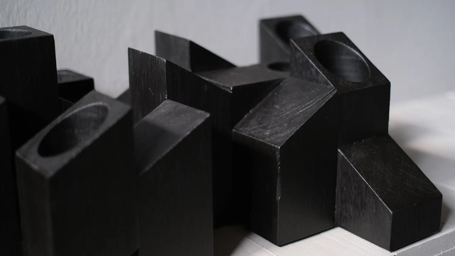Close-up of the carved candle openings and angular black wooden forms of the Skyline Candle Light by Arno Declercq.
