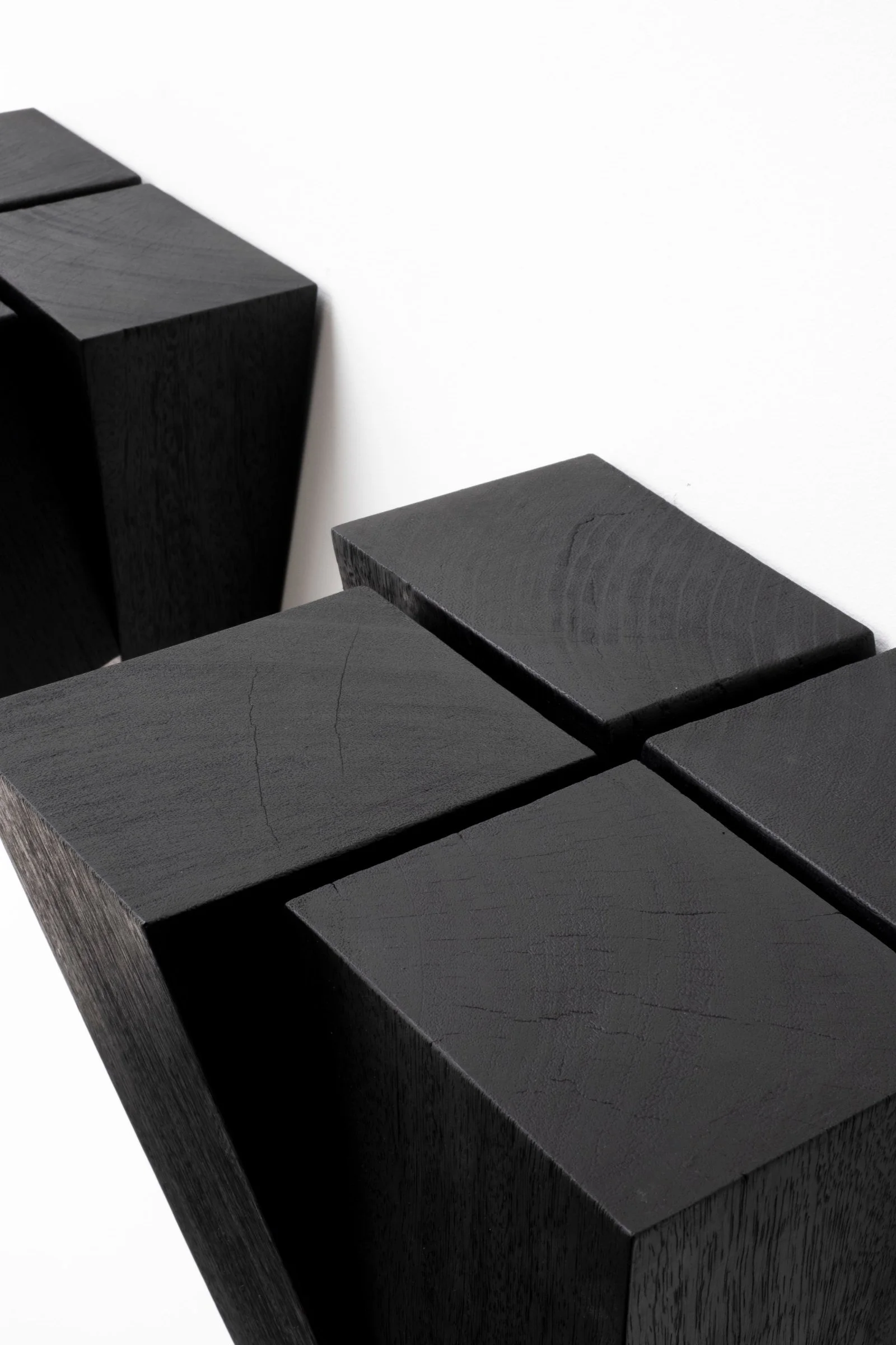 Close-up of the intersecting burned Iroko surfaces of the Umbo Wallstand by Arno Declercq.