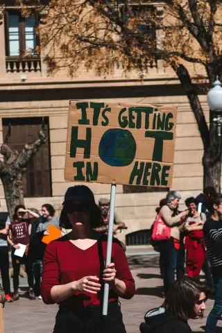 Climate protester holding an “It’s Getting Hot in Here” sign at a public demonstration