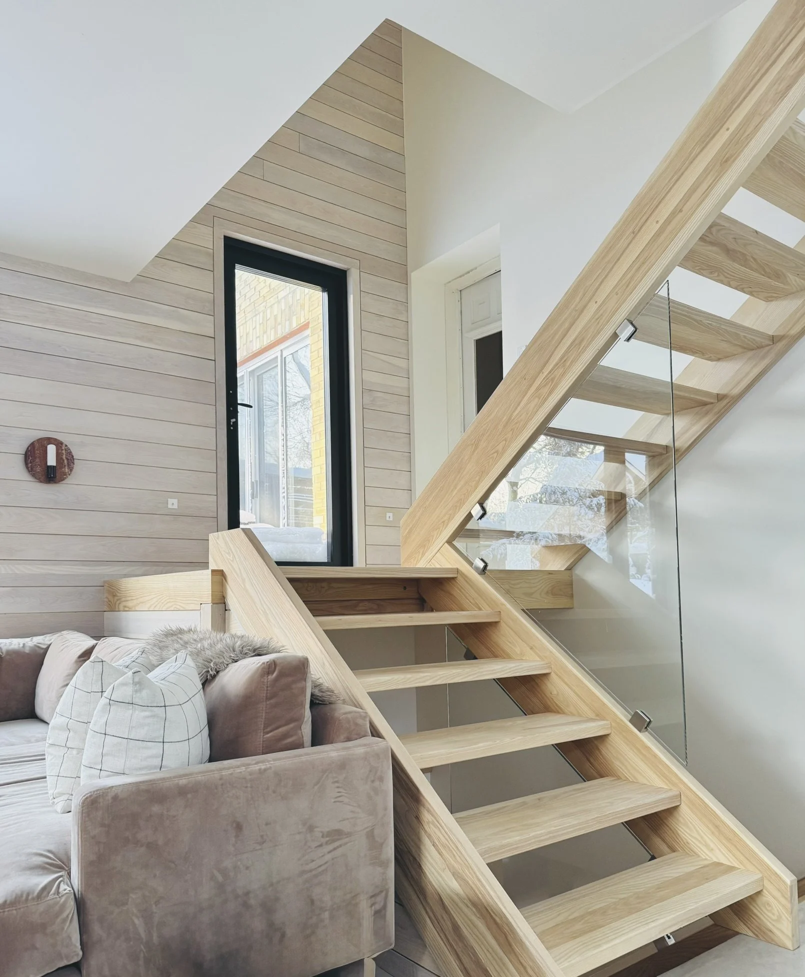 Open ash wood staircase at Hinterhaus 41 by Elevin Design Studio leading to a second-level cabin, featuring modern minimalist detailing, warm natural finishes, and a velvet couch, contemporary residential interior, photo by Brad and Shawn Hernden