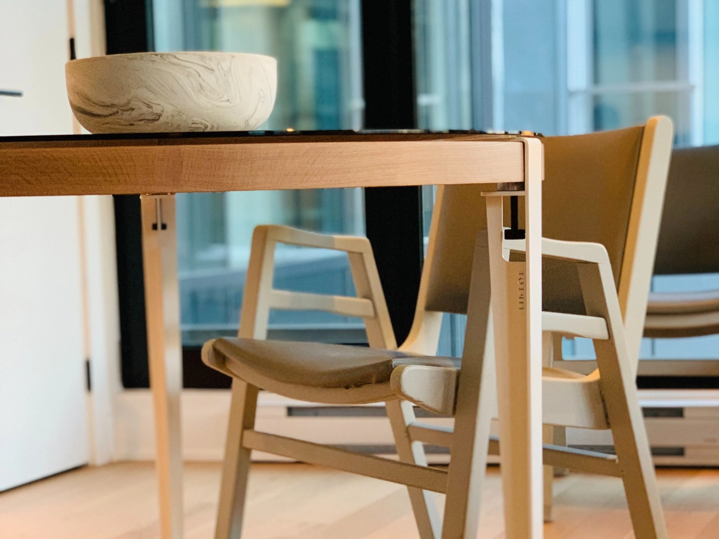 A round smoked glass dining table with white steel TipToe legs and white oak base_at Quartier General Montreal_designed by Brad + Shawn Hernden_The Superhost Mentors for Elevïn Design Group