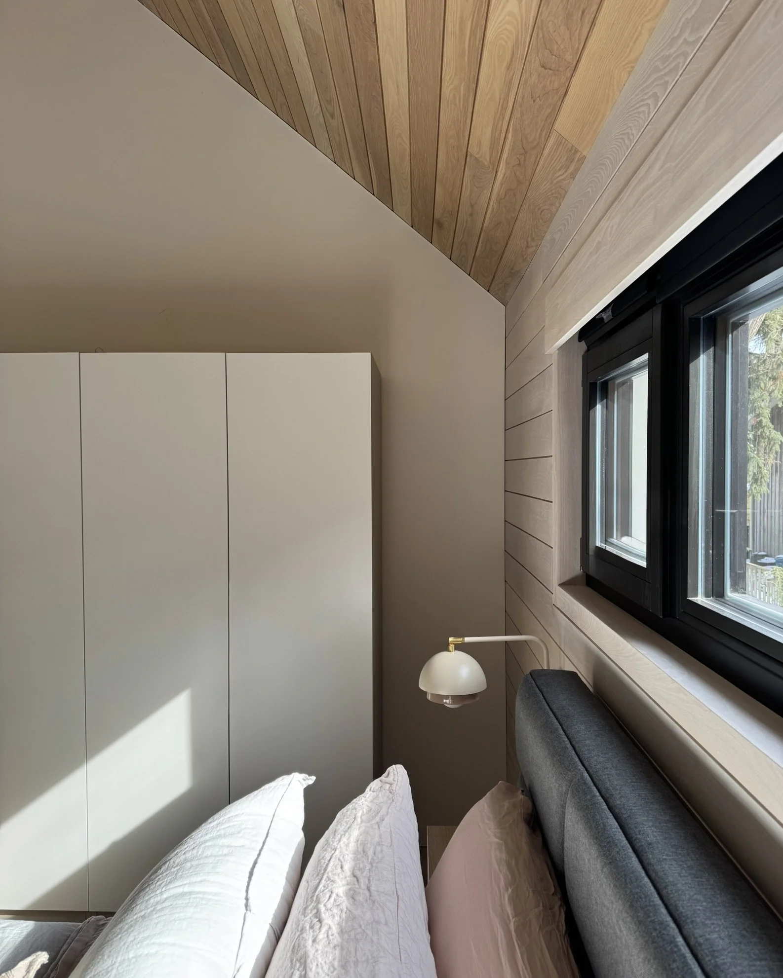 Cathedral ceiling in ash wood at Hinterhaus 41 by Elevin Design Studio with European-style black windows and white walls, modern residential interior, photo by Brad and Shawn Hernden