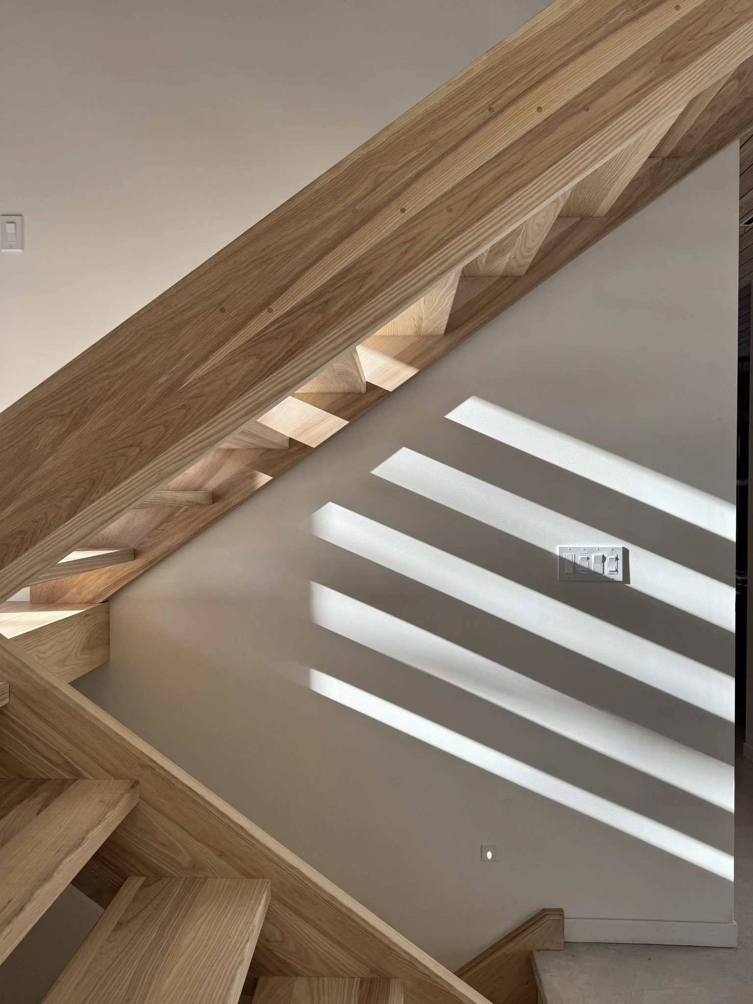 Open ash wood staircase at Hinterhaus 41 by Elevin Design Studio leading to a second-level cabin, featuring modern minimalist detailing and warm natural finishes, contemporary residential interior, photo by Brad and Shawn Hernden