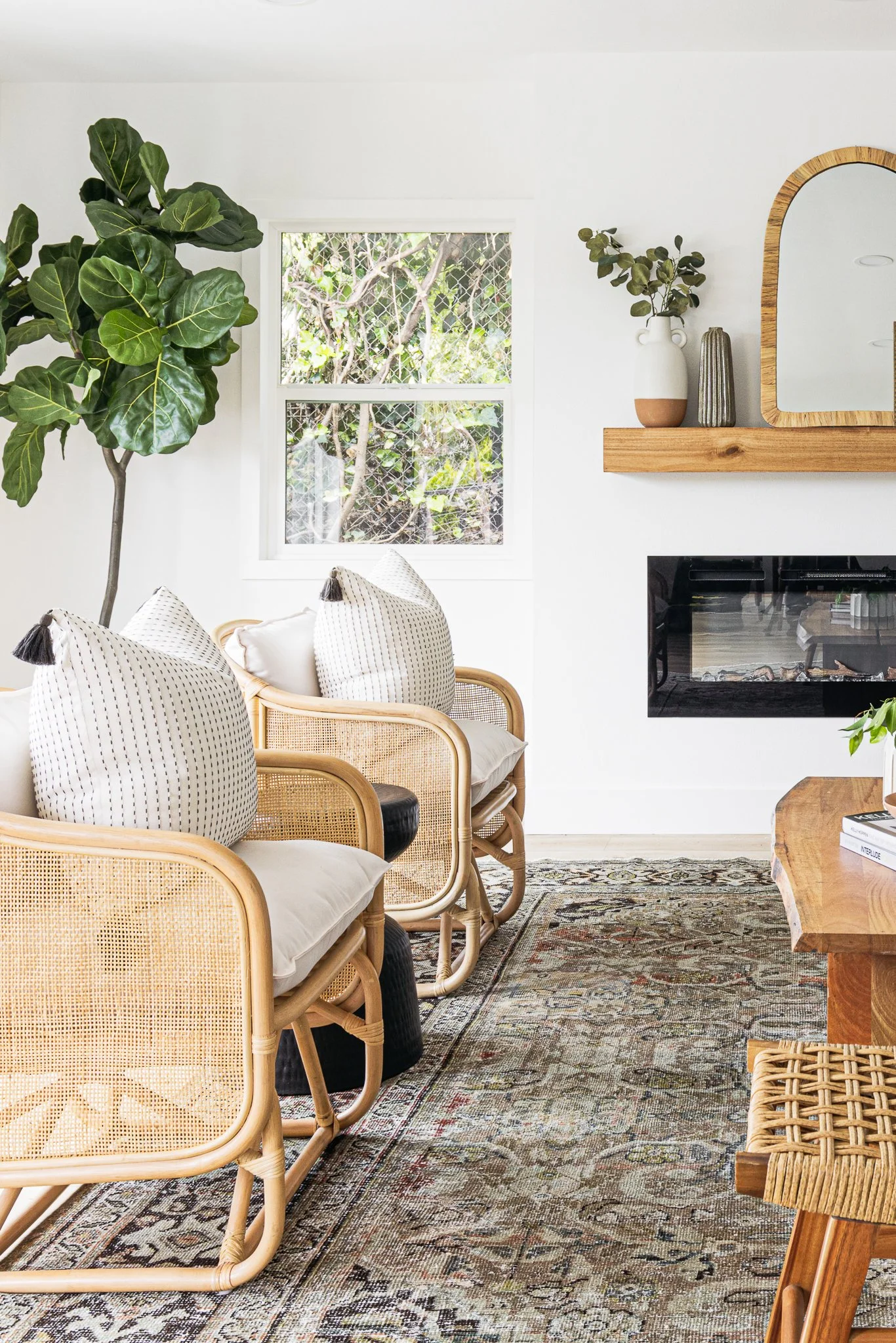 living room design. two wicker chairs, black fireplace, and light wood accents