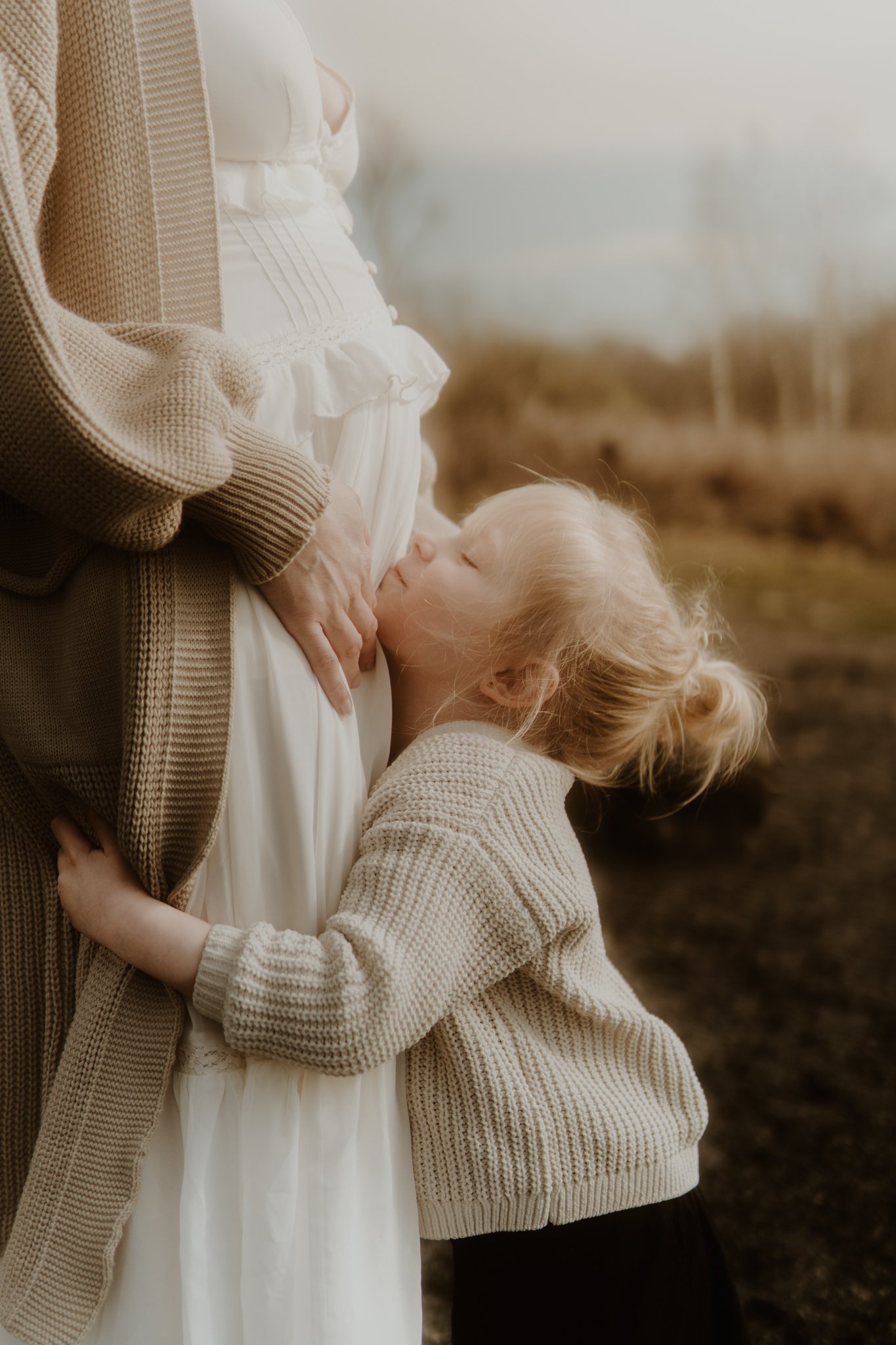 little girl cuddles up to mom's belly