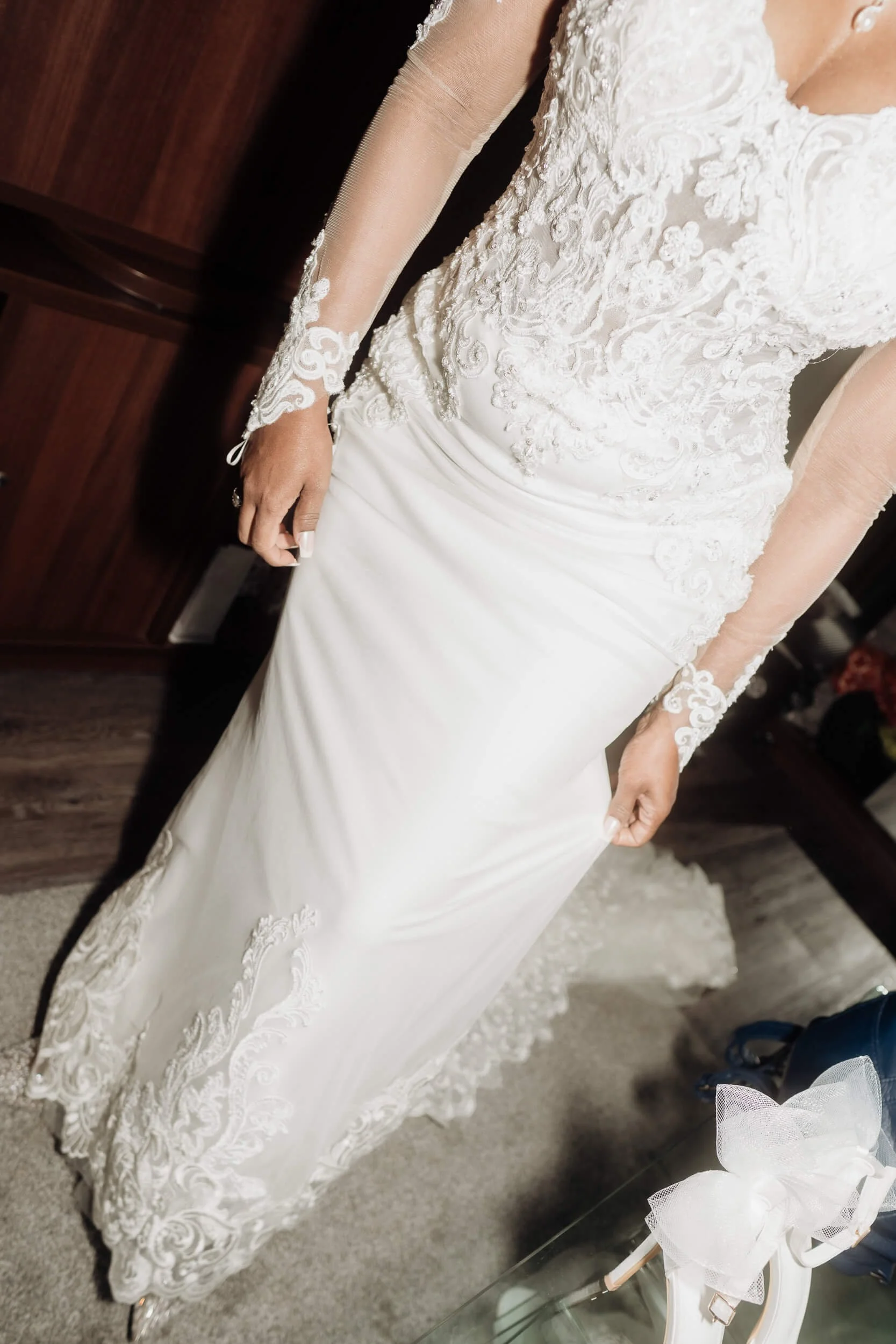 Bride wearing a white wedding gown with lace details and long sheer sleeves.