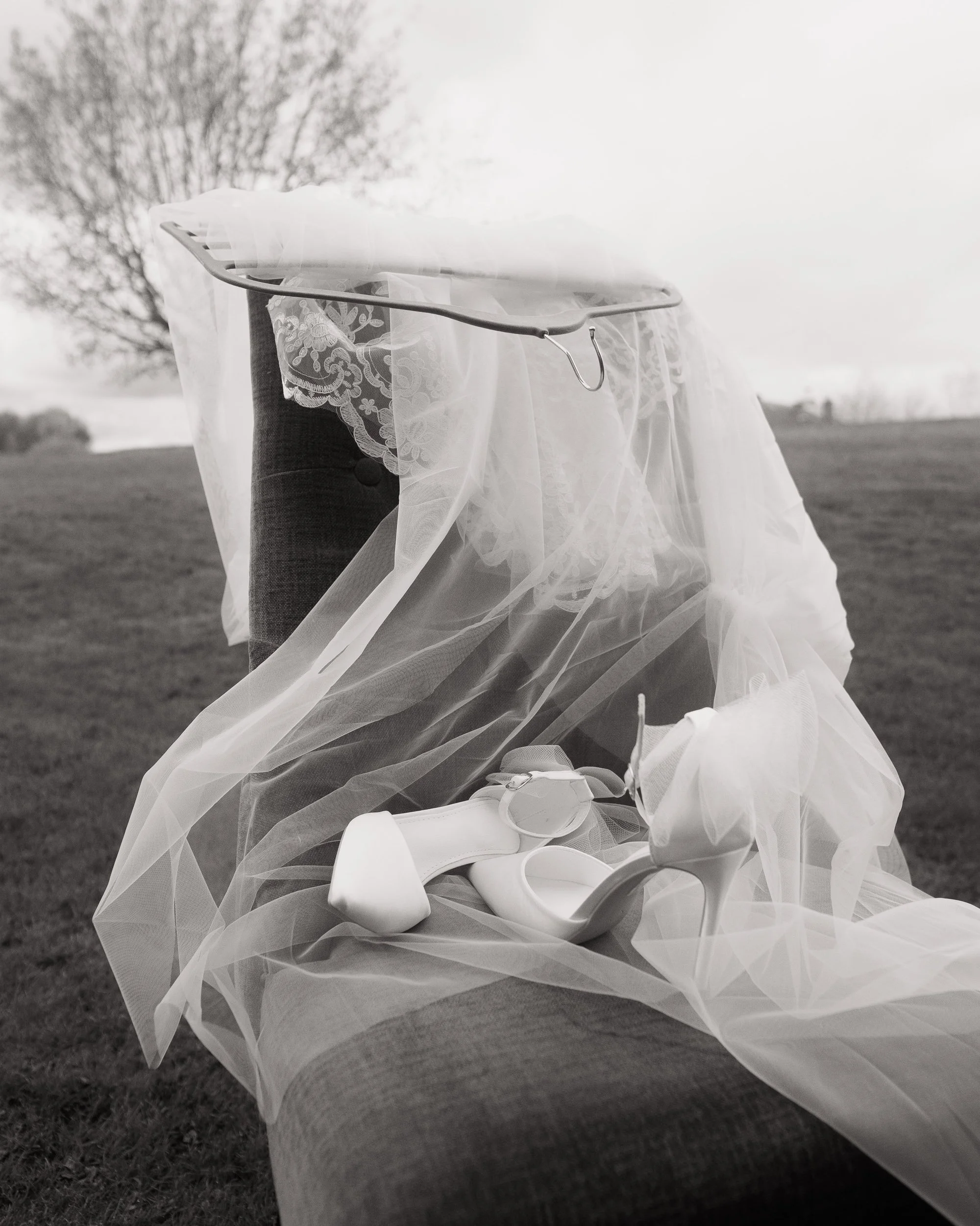 black and white bridal shoes and veil on a chair outdoors