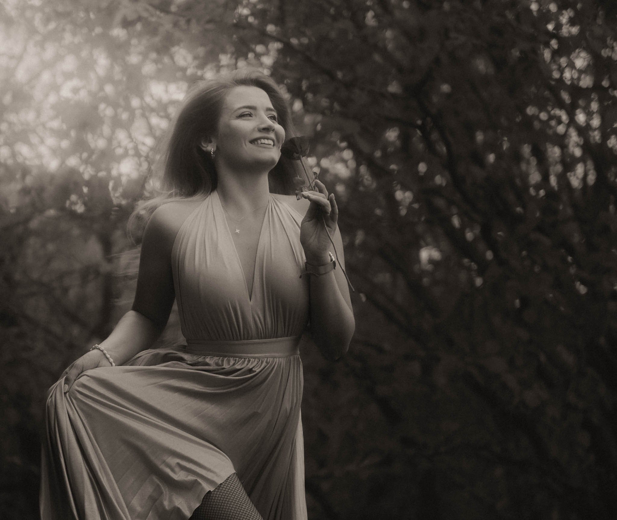 a long haired girl runs across the meadow with a rose in her hand