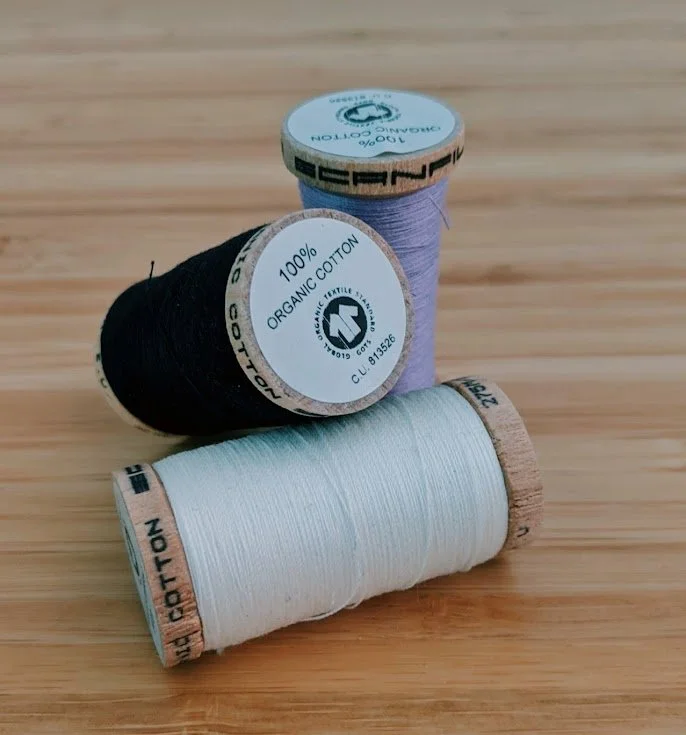 Spools of scanfil thread in white, black and lilac
