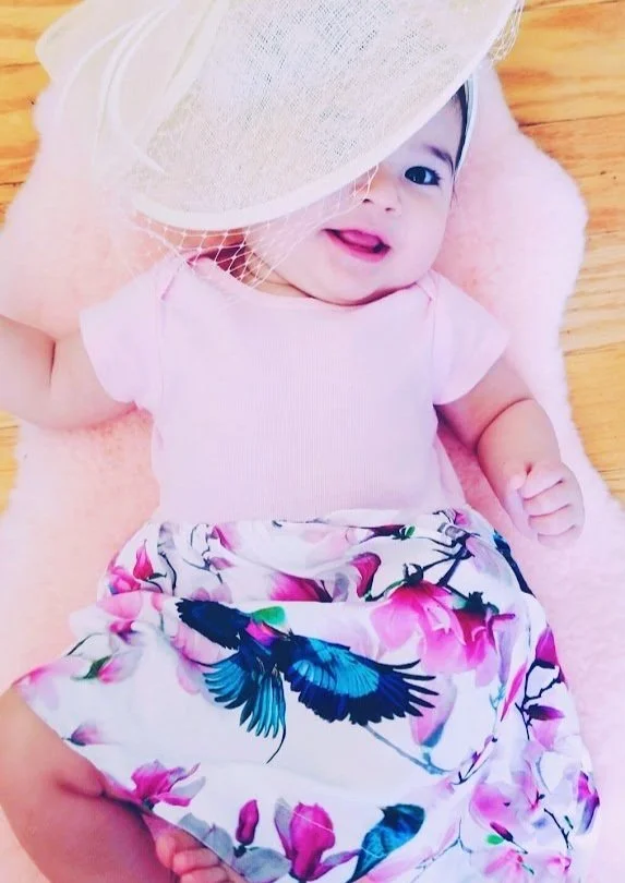 Baby in pink dress with bird print skirt and hat