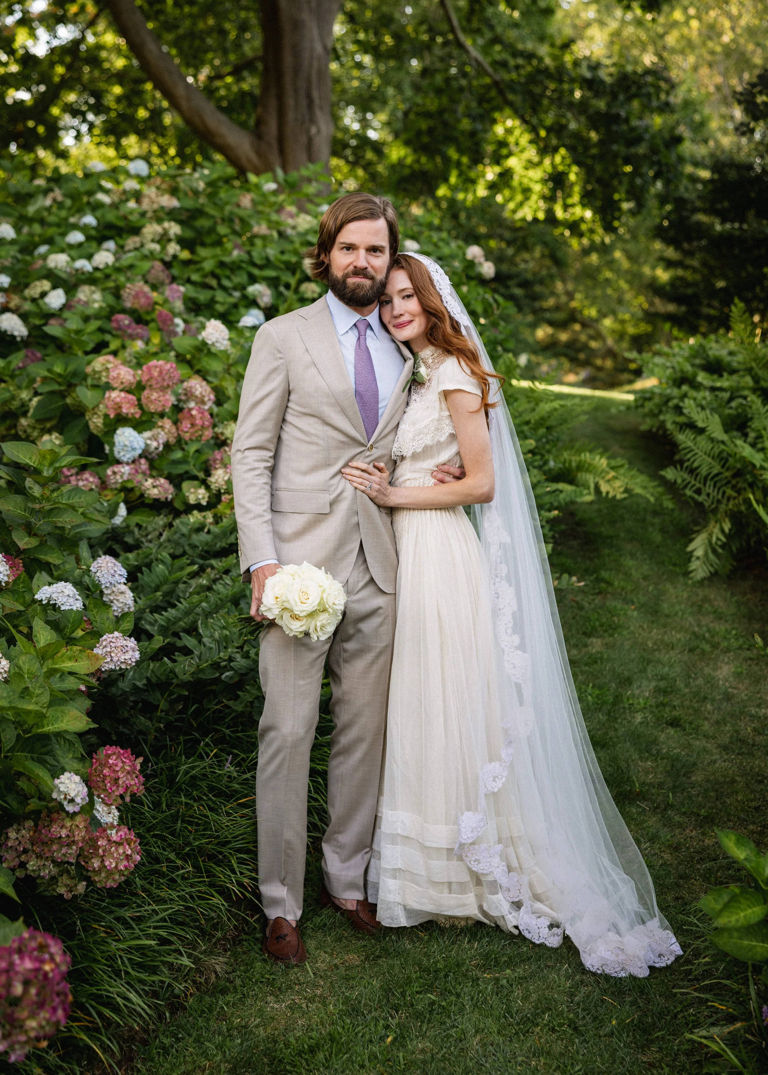 Bride in a dress from 1905 with vintage veil in garden with groom