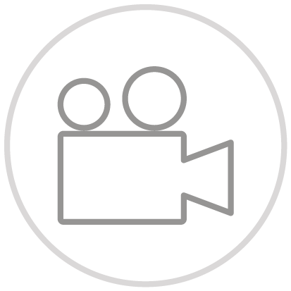 Gray video camera icon with lens and reel symbols inside a circle on a white background.