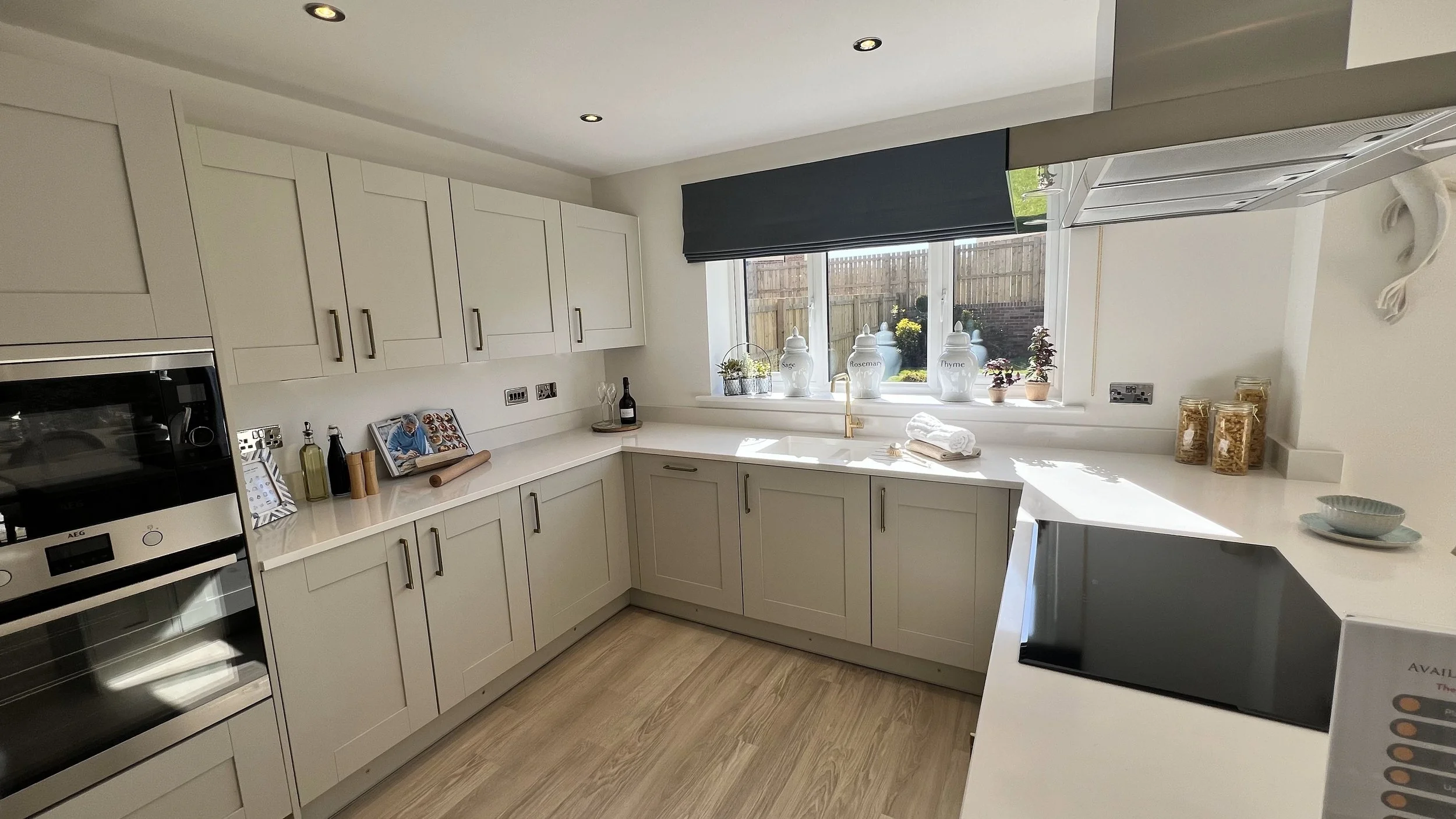 Modern kitchen with white cabinets, a built-in oven, and a window with herb jars on the ledge.