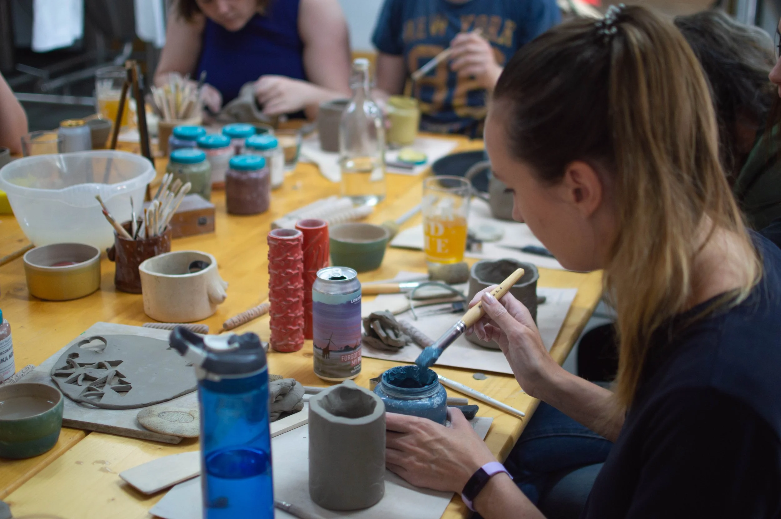 Friends painting and decorating pottery together during a team-building pottery session.